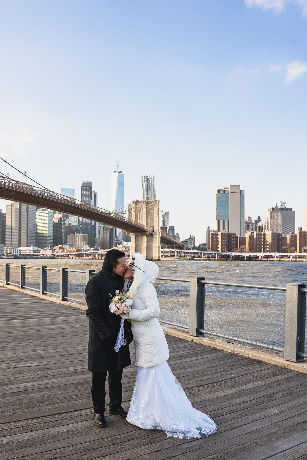 Couple kissing with the Manhattan skyline behind at Brooklyn Bridge Park